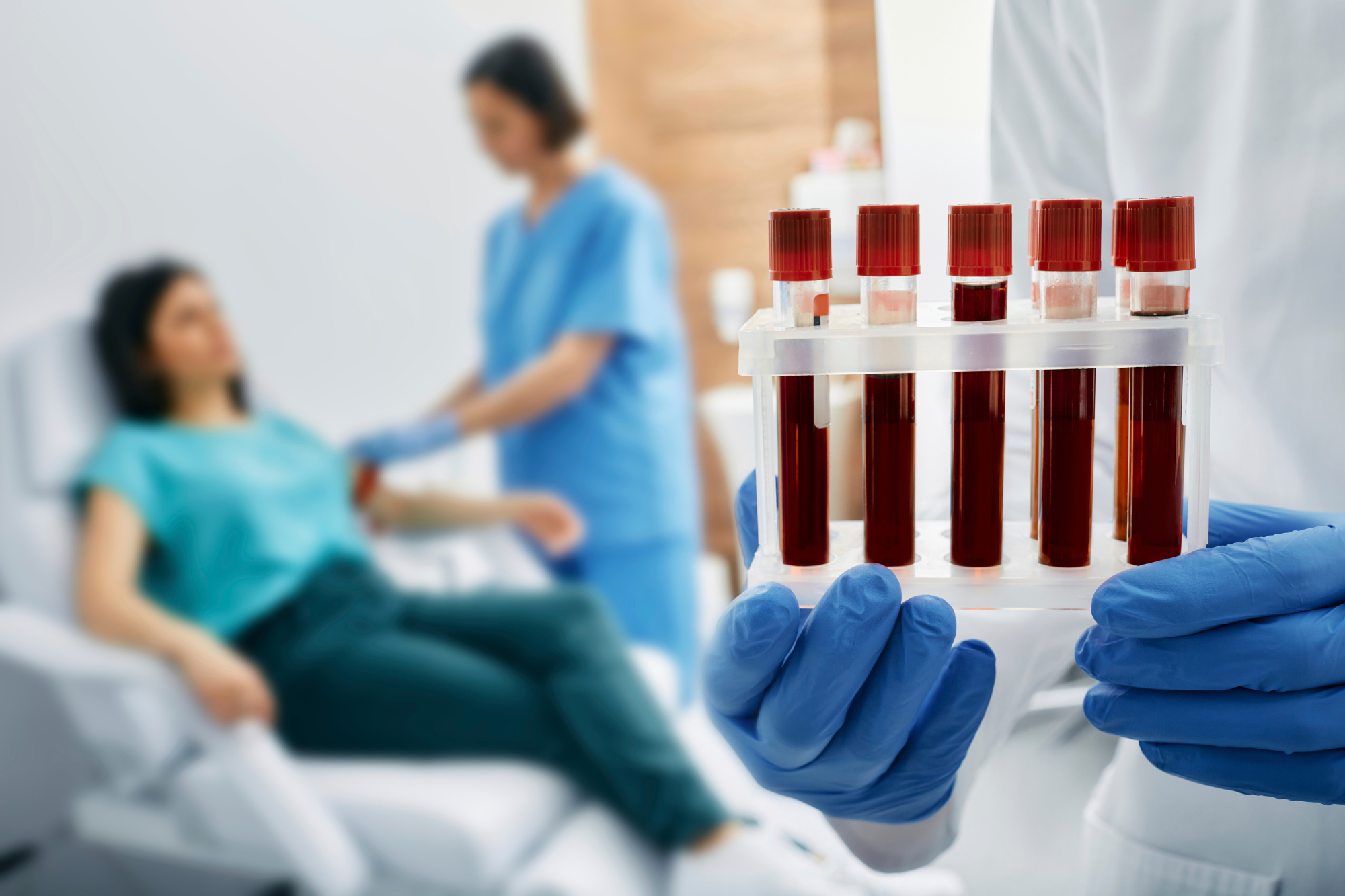 A tech holds a rack of blood-filled tubes near a patient, representing the question, How often should you get bloodwork done?