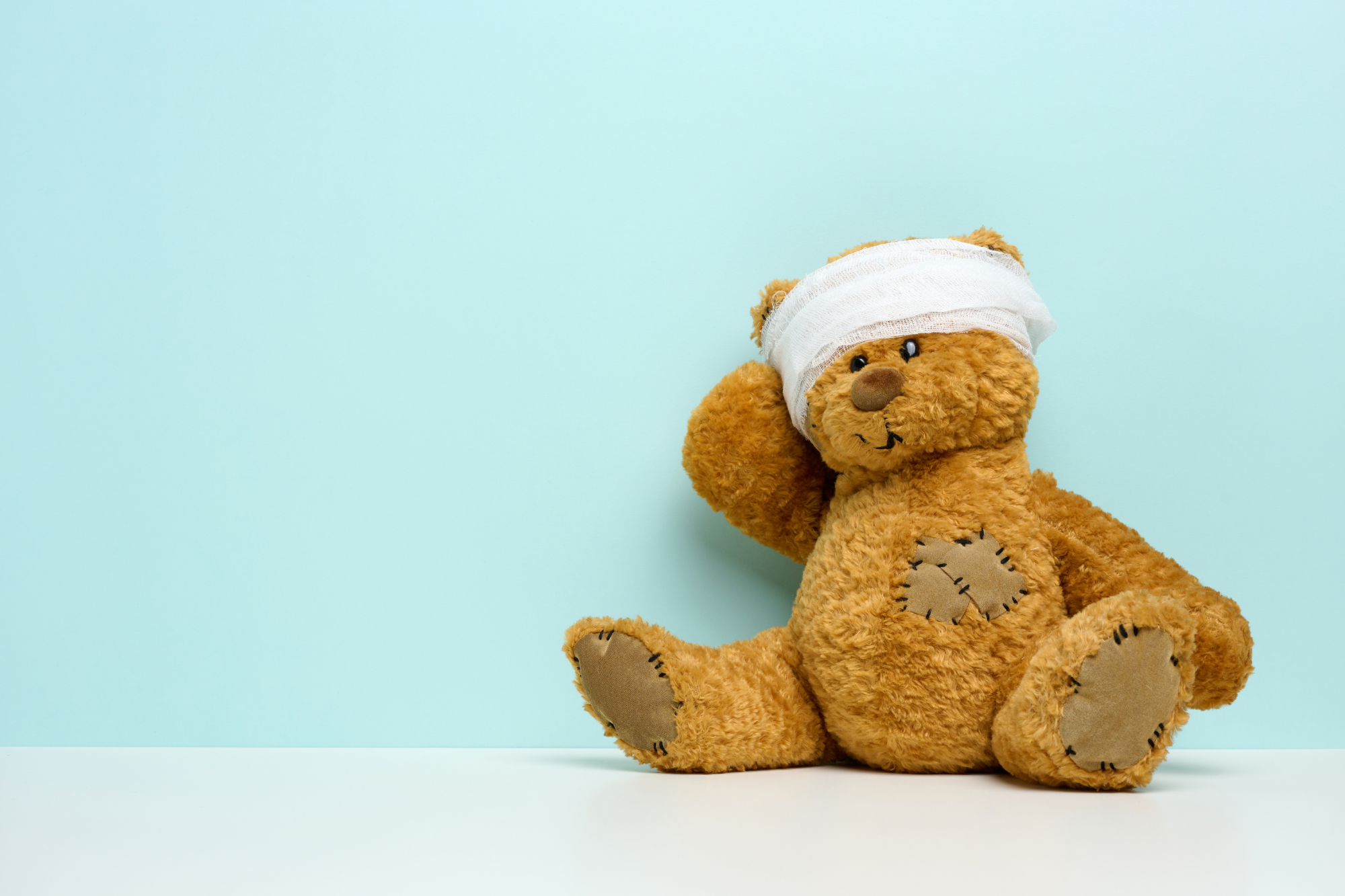A teddy bear with a bandage around his head represents the effects of childhood trauma in adulthood.