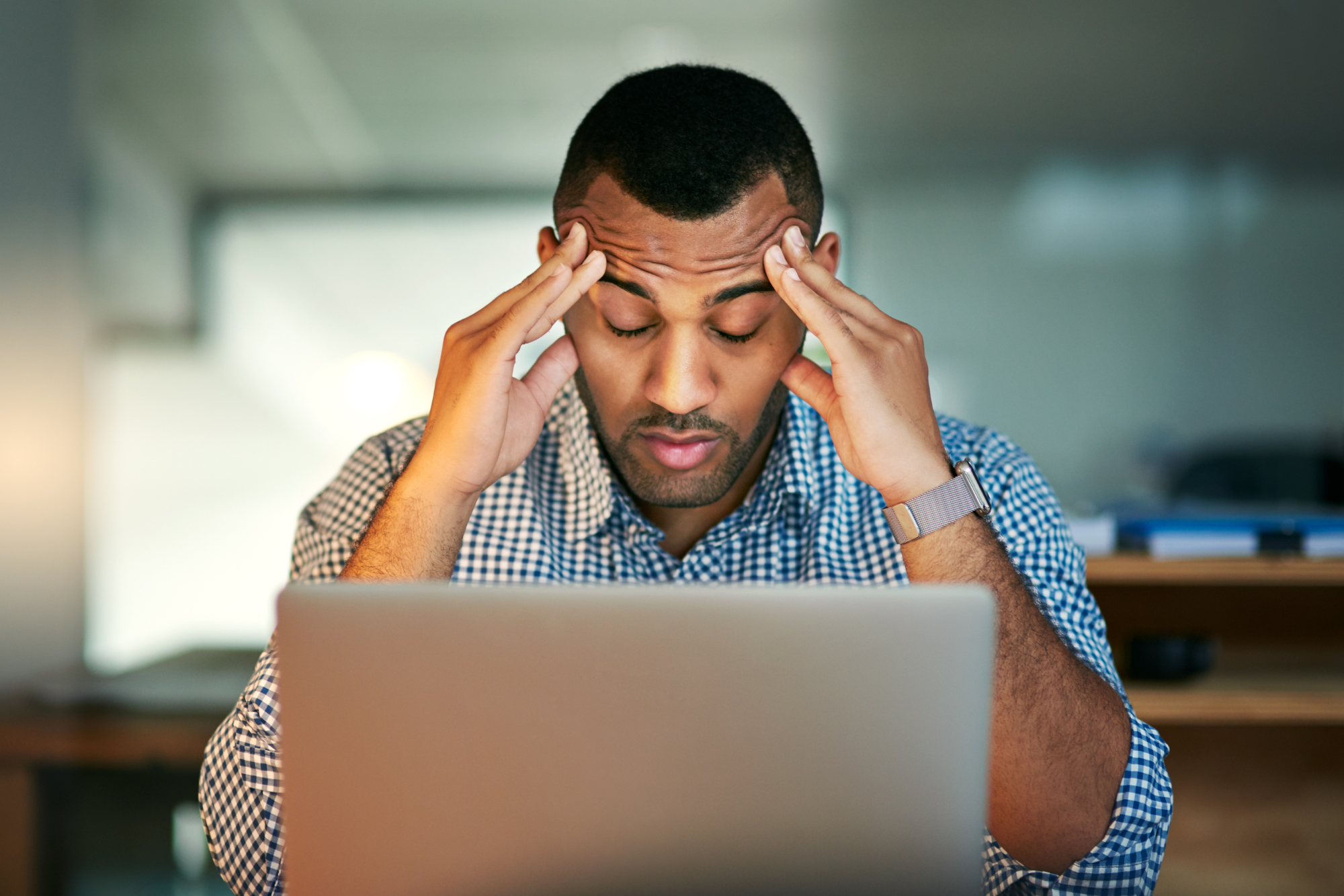 Man stressed with work at a laptop.