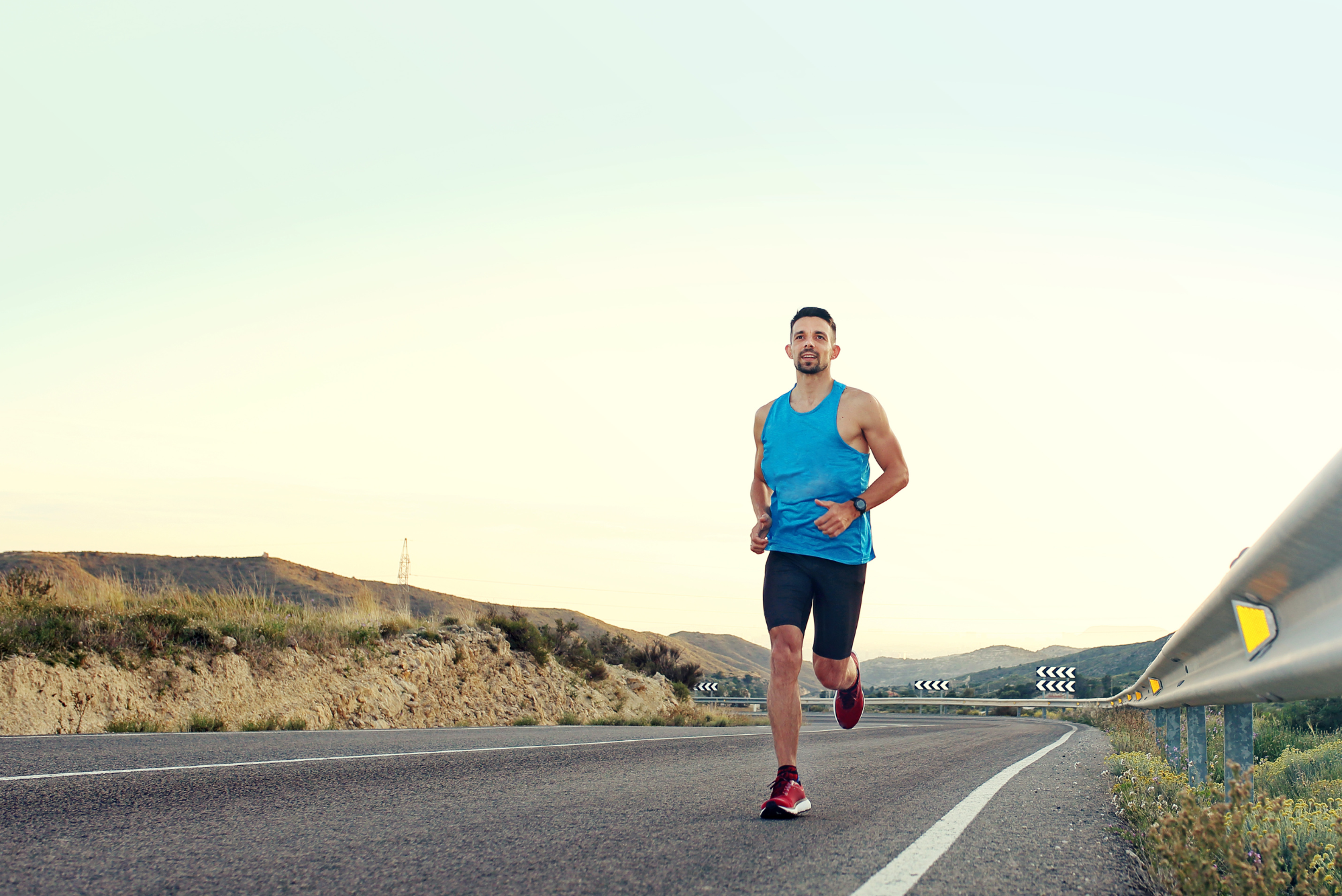 Runner maintaining steady pace on open road during golden hour.