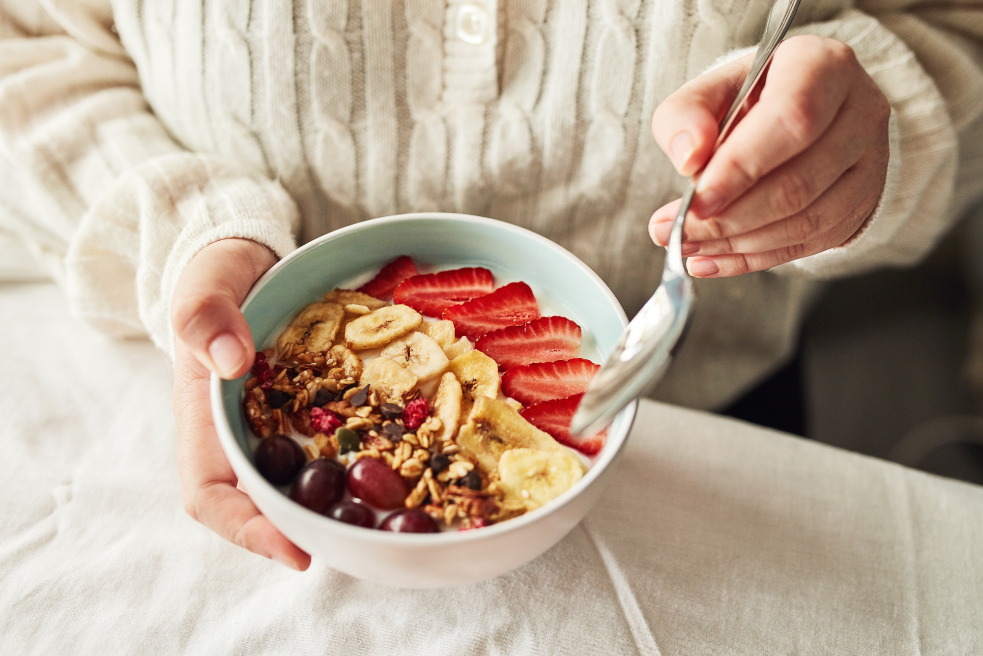 Healthy breakfast bowl with fresh strawberries, bananas, nuts, and seeds.