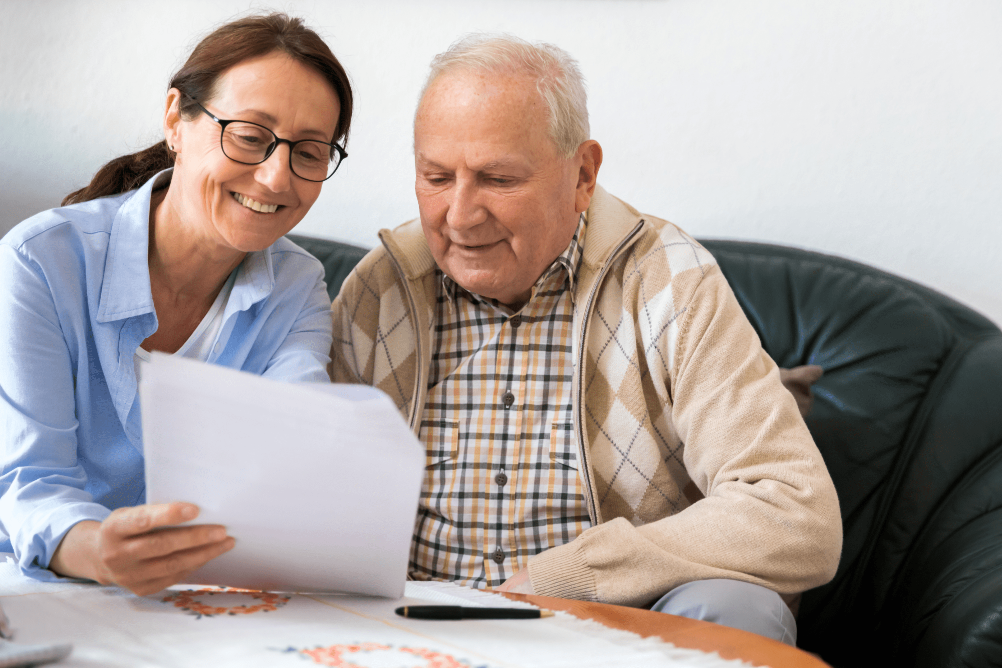 Smiling female discusses metabolic health markers with an elderly male while reviewing documents at table.