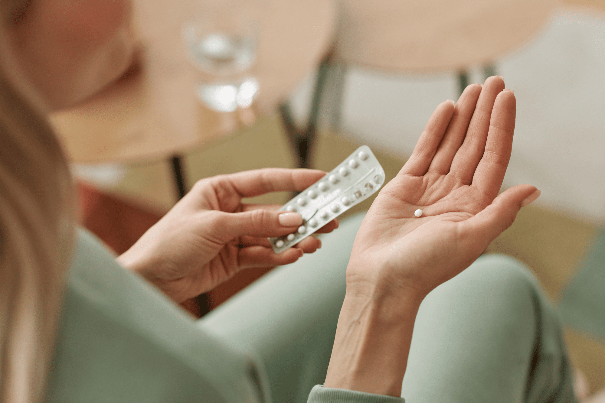A woman holding a birth control pill.