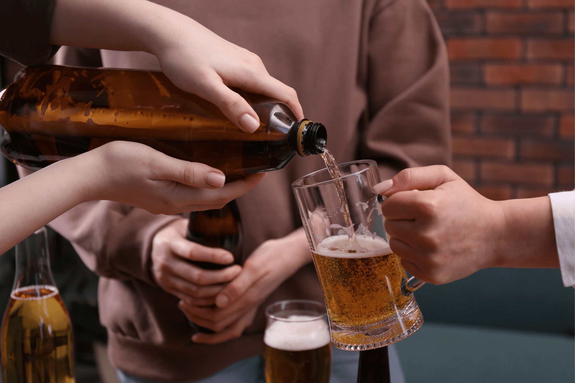 A person pouring beer from a bottle into a glass mug.