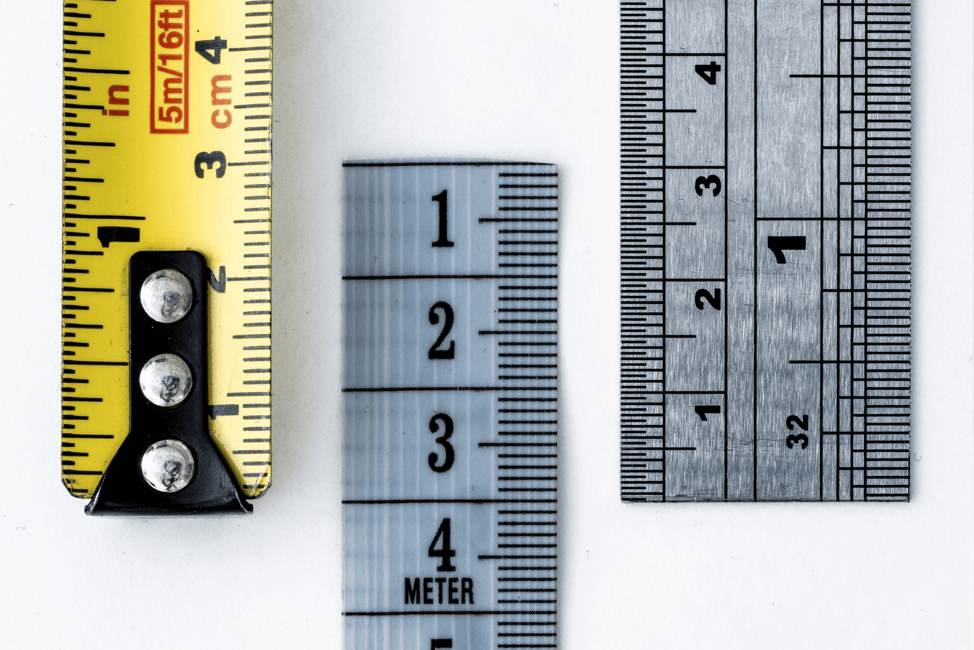 Three measuring tools showing inch, centimeter, and fractional ruler markings side by side, illustrating precision like an ApoB test.