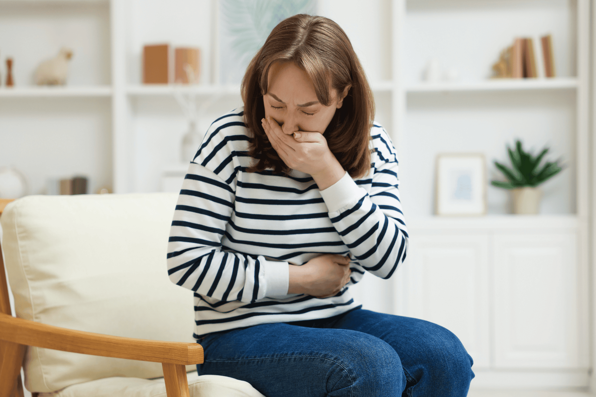 Woman at home holding her stomach in discomfort, wondering if perimenopause can cause nausea.
