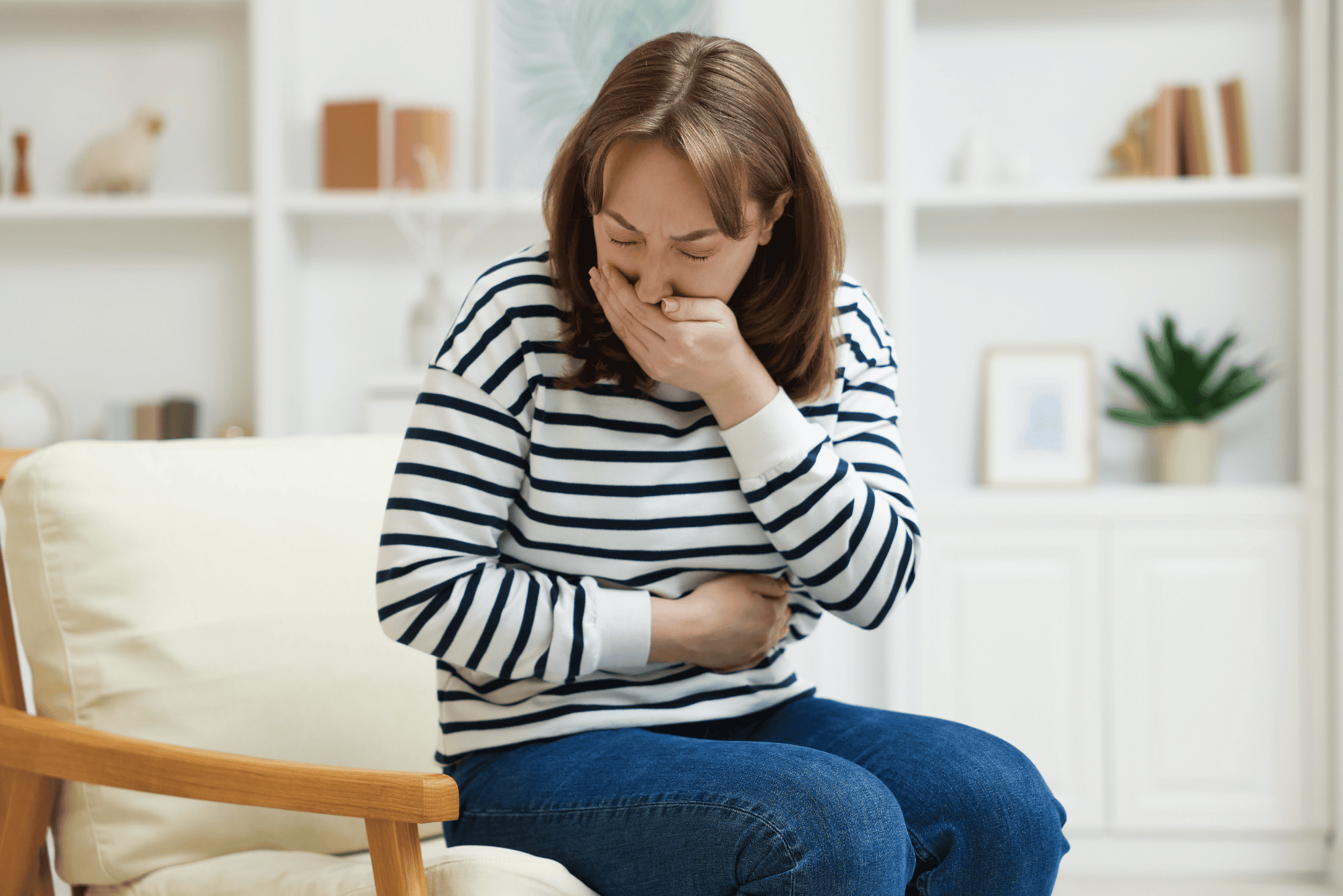 Woman at home holding her stomach in discomfort, wondering if perimenopause can cause nausea.