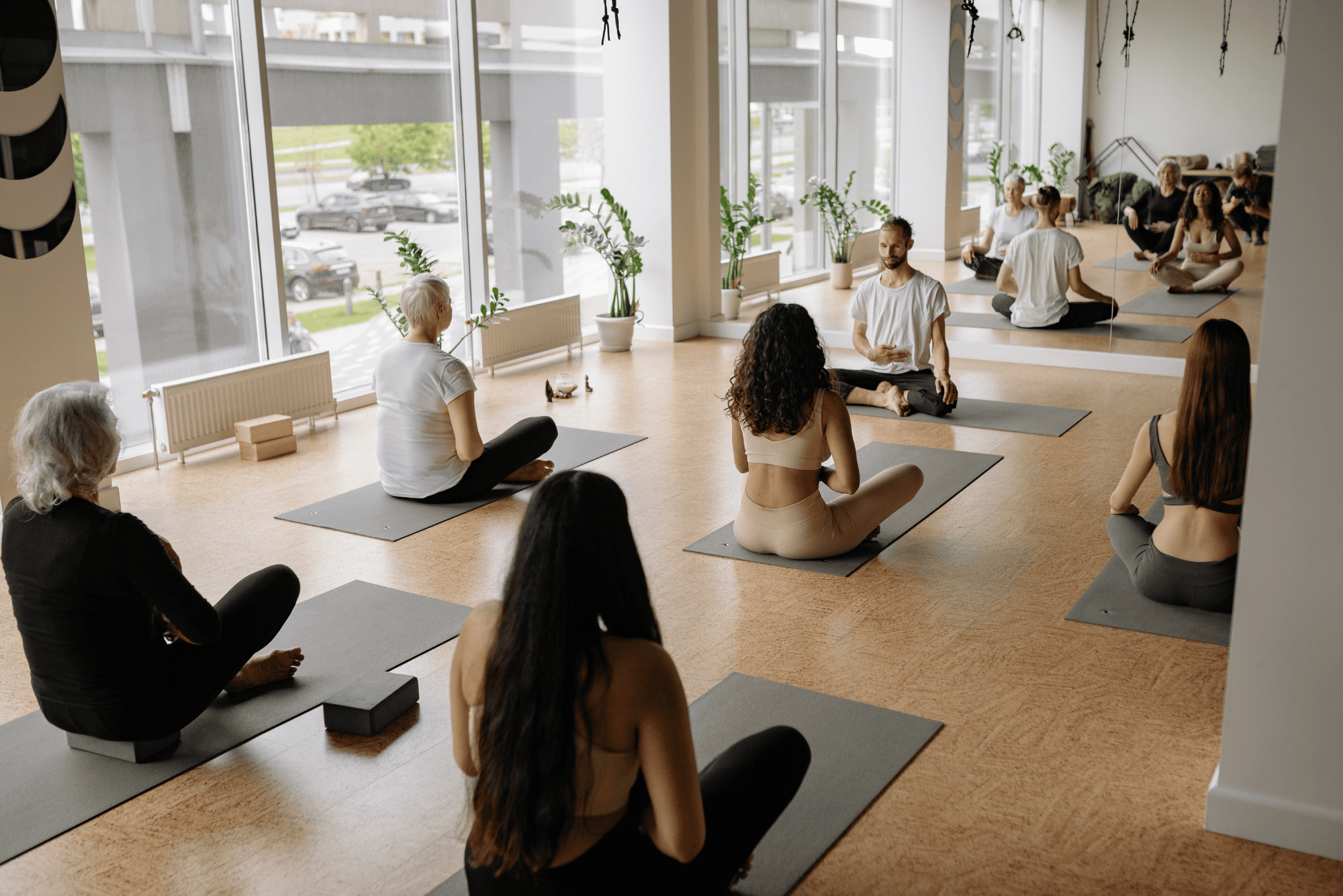 A group sits cross-legged on mats in a bright studio, illustrating one of the vagus nerve stimulation exercises.