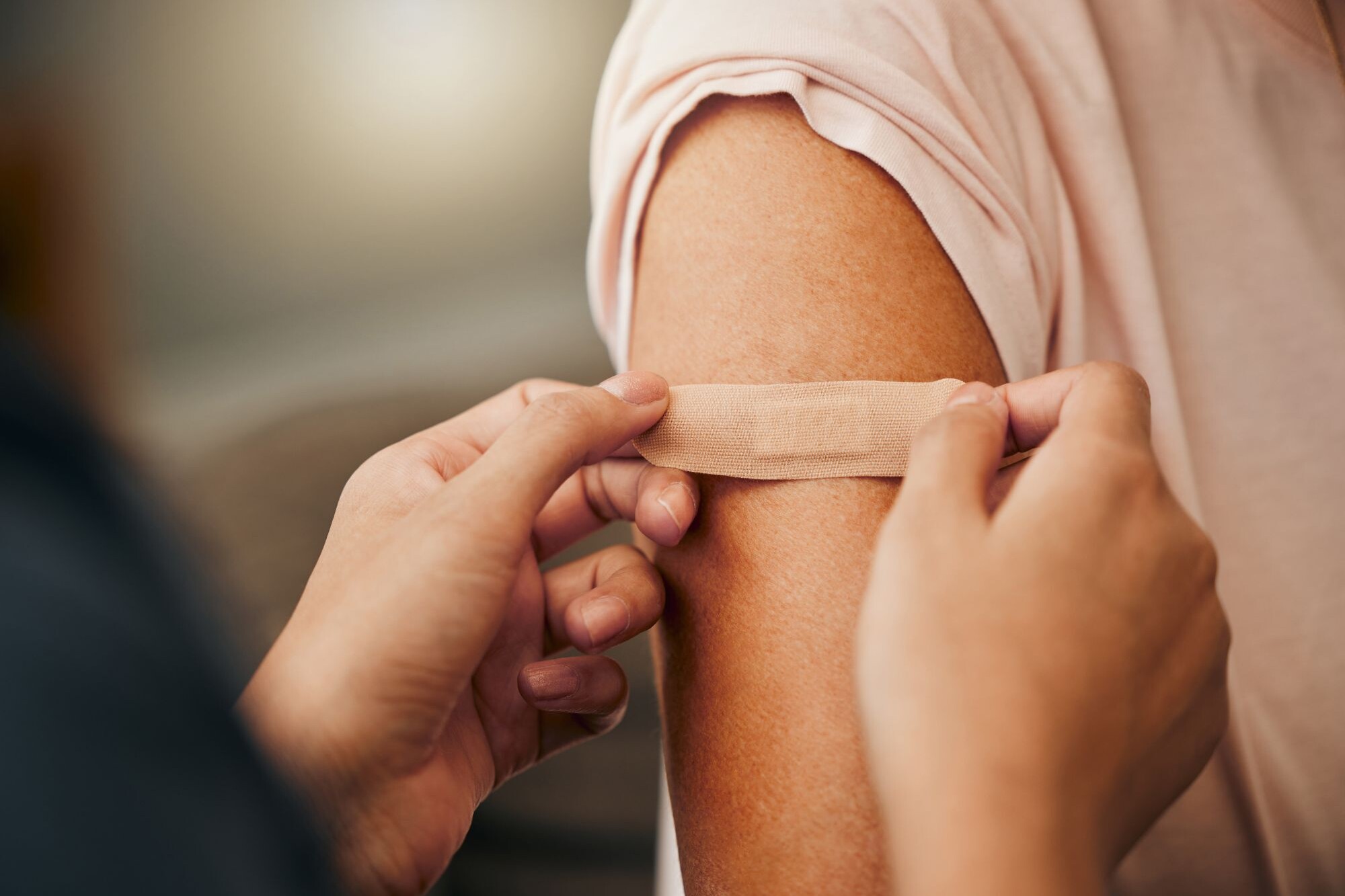 A nurse puts a Band-Aid on her patient’s arm after administering their annual flu vaccine.